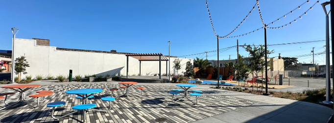 Image of Centennial Plaza with colorful tables, string lights, and small stage.